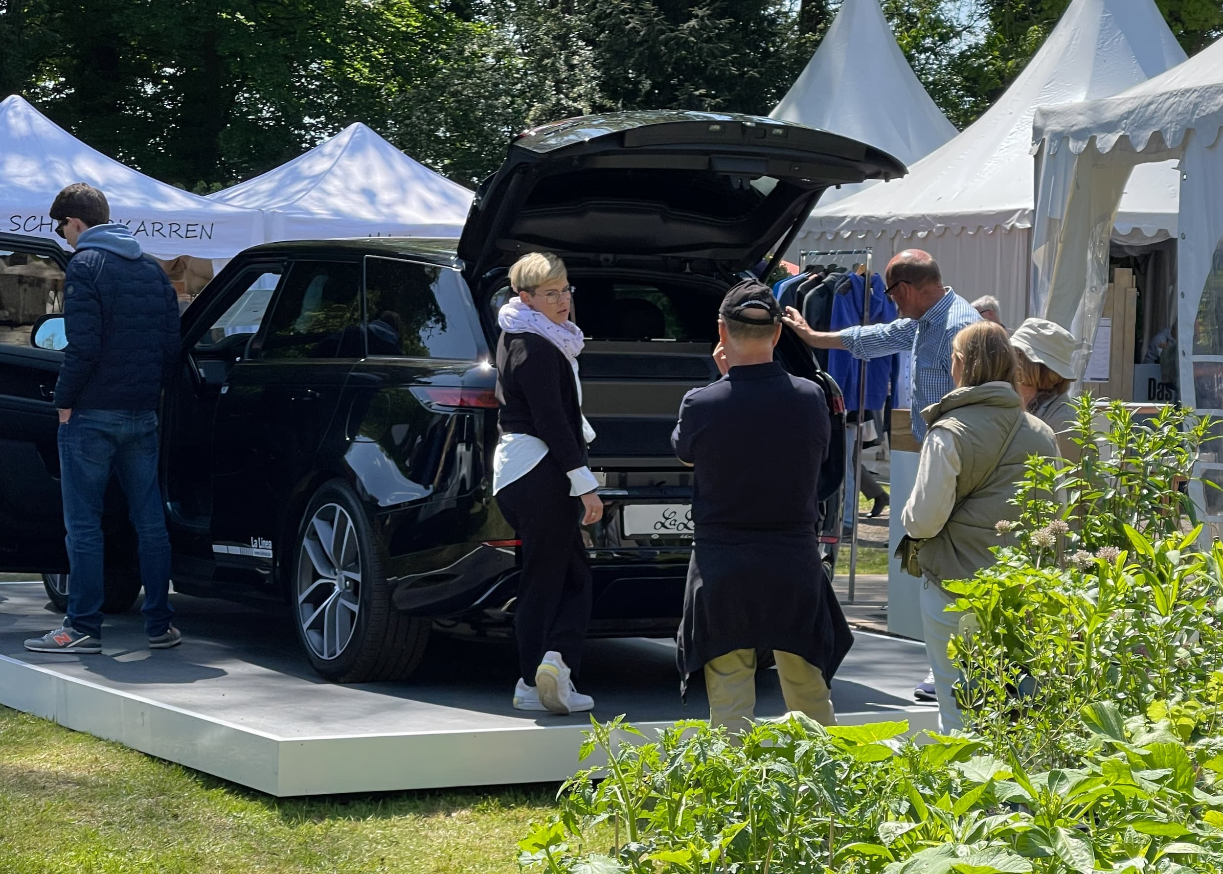 Visitors looking into the open boot of a black Range Rover Sport at an outdoor event.