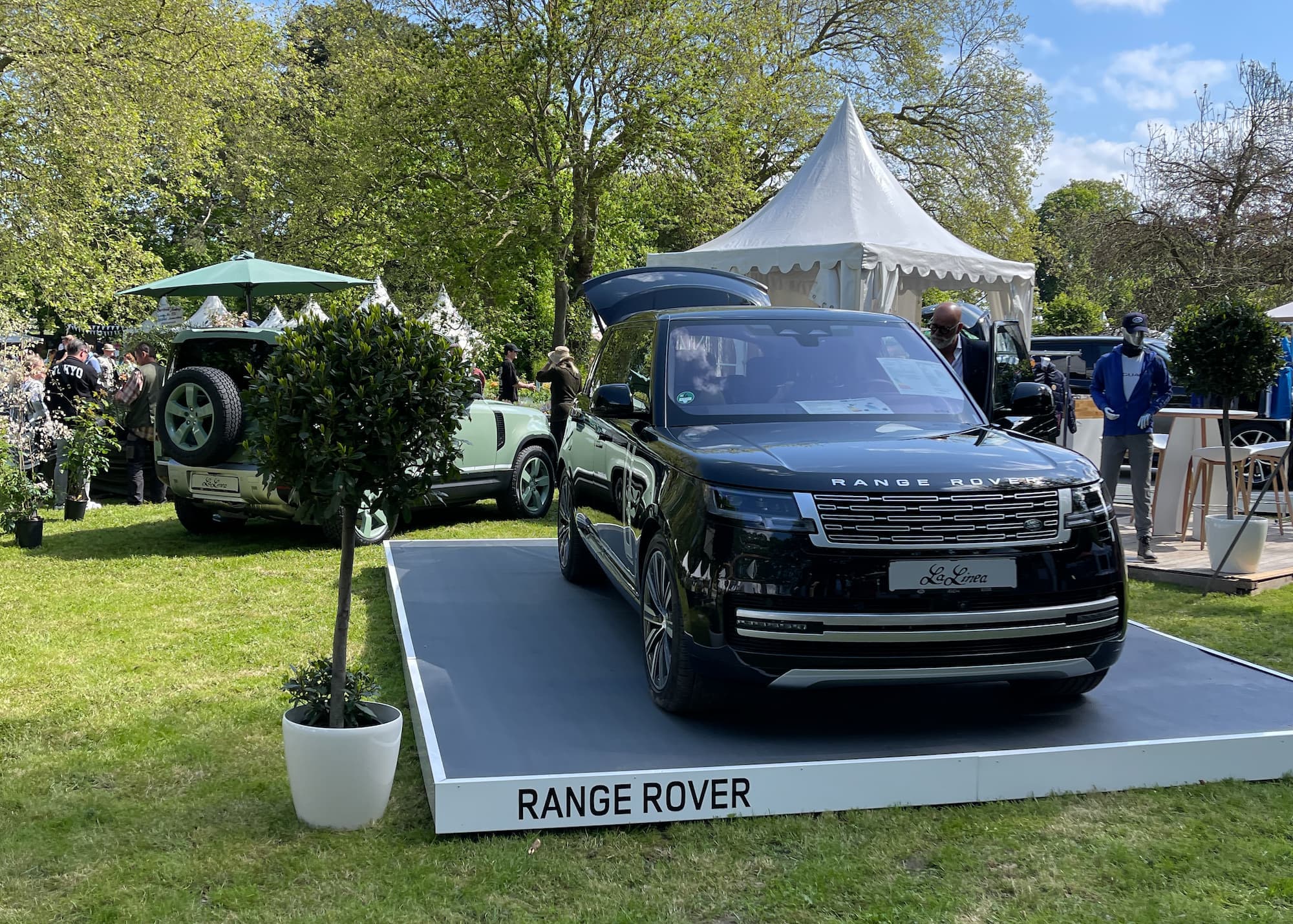 A black Range Rover on a display plinth at an outdoor car event in Germany.